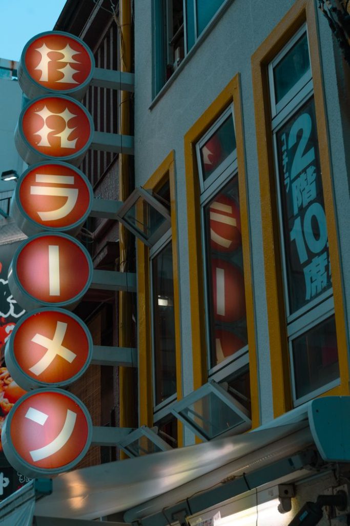 A neon ramen sign lights up a street in Tokyo, showcasing Japanese street culture.